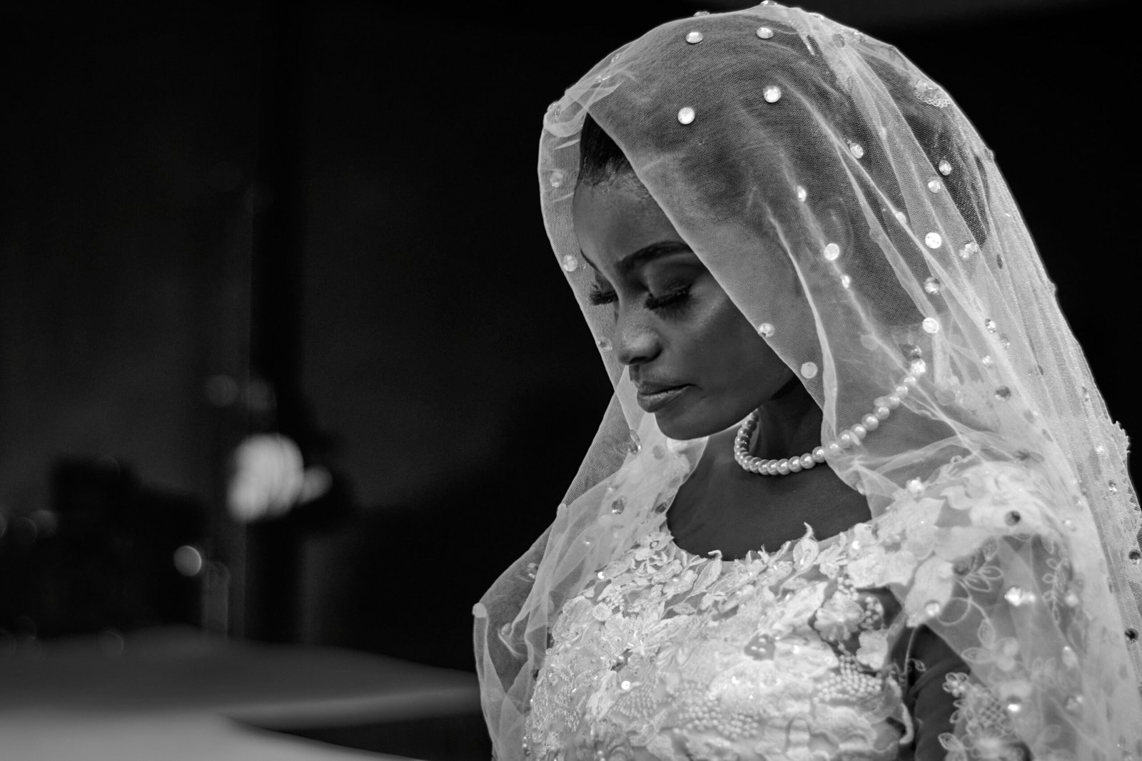 Black and white portrait of a beautiful African bride in a traditional wedding dress and veil.